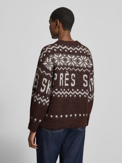 Frauenmodel trägt Pullover mit Ballonärmeln von VERO MODA, braun mit weißem geometrischen Allover-Muster, Strickoptik, Ganzkörperansicht Rückansicht.