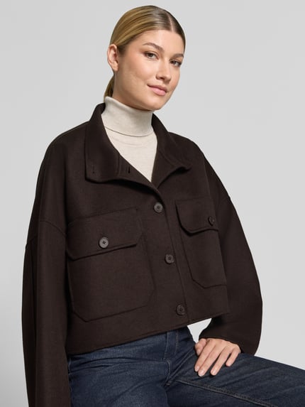 Frauenmodel trägt Boxy Fit Jacke mit Stehkragen Modell 'ARKLOW' von DRYKORN aus Baumwoll-Mix in Dunkelbraun, Nahaufnahme Oberkörper.