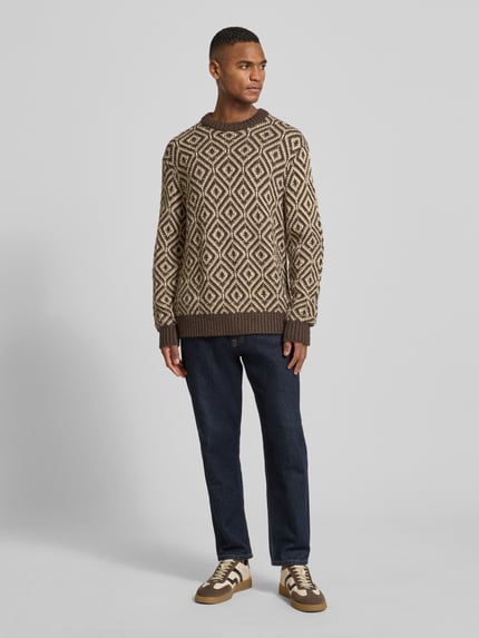 Männermodel trägt Relaxed Fit Strickpullover aus Woll-Mix Modell 'REMI' von SELECTED HOMME mit Allover-Muster, Ganzkörperansicht von vorne.