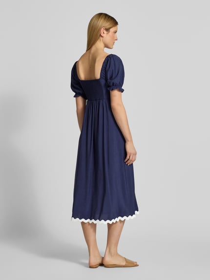 Frauenmodel trägt Tunikakleid mit Karree-Ausschnitt von Apricot in Dunkelblau, A-Linie, Midikleid, 1/2-Arm, Rückansicht Ganzkörperansicht. Rückenlänge bei Größe S: 120 cm, Brustweite bei Größe S: 40 cm, Ärmellänge bei Größe S: 30 cm, elastische Ärmelabschlüsse, weißer Saum.