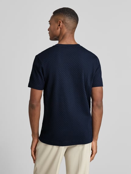 Männermodel trägt T-Shirt mit geripptem Rundhalsausschnitt von JOOP! Collection aus reiner Baumwolle, Regular-Fit, Rückenlänge 68 cm, Ganzkörperansicht Rückansicht.