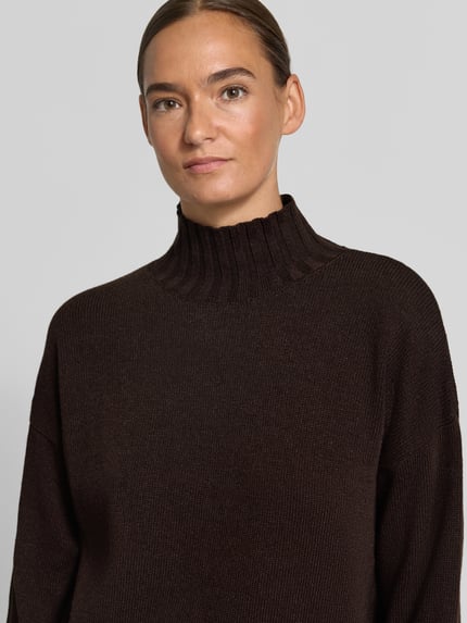 Modelka kobieca nosi Strickpullover aus Woll-Mix mit Stehkragen od Milano Italy, kolor ciemnobrązowy, relaxed fit, kaszmir, prążkowany kołnierz, opuszczone ramiona, długość tyłu 51 cm, długość rękawa 52 cm, zbliżenie na górną część ciała.