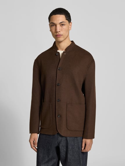 Männermodel trägt Hemdjacke mit Stehkragen von Officine Générale in Braun, unifarben, strukturierte Filzoptik, aufgesetzte Taschen, Ganzkörperansicht von vorne