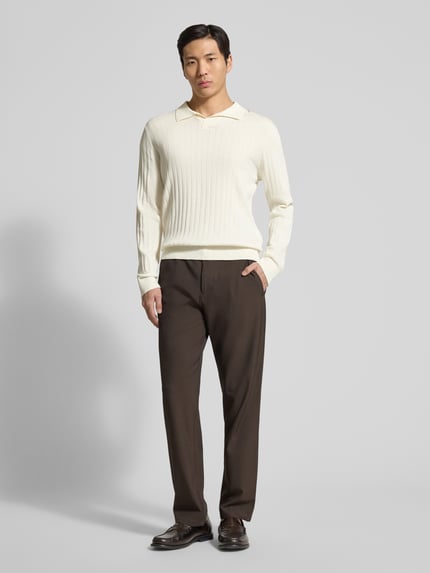 Männermodel trägt Loose Fit Poloshirt aus reiner Baumwolle Modell 'TORINO' von SELECTED HOMME in Creme, unifarben, Rippstruktur, Ganzkörperansicht von vorne.