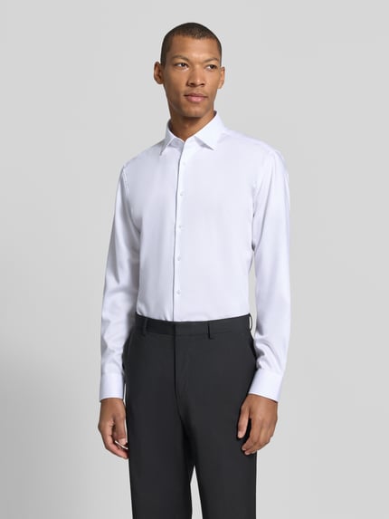 Męski model nosi białą koszulę Slim Fit Businesshemd aus reiner Baumwolle Modell 'New Kent' von Seidensticker, garnitur szary, zdjęcie całej sylwetki z przodu, koszula biznesowa męska od Seidensticker.