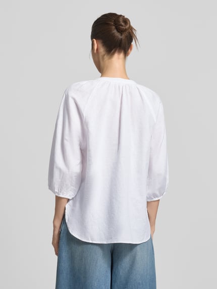 Vrouwenmodel draagt Relaxed Fit Hemdbluse Leinen-Baumwoll-Mix Modell 'ALBERTA' van Selected Femme, wit, unikleur, 3/4-mouw, afgeronde zoom, eenreihige knopen, achterkant volledig, raglanmouwen, materiaalmix. Ganzlichaansicht achteraan.