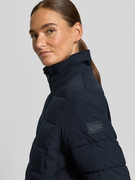Frauenmodel trägt Jacke mit abnehmbarer Kapuze Modell 'ECLIPSE' von NAUTGÅRD in Dunkelblau, strukturierte Oberfläche, Nahaufnahme Oberkörper. Rückenlänge 79 cm, Zweiwege-Reißverschluss, Label-Patch, gestrickte Ärmelabschlüsse, seitliche Eingrifftaschen mit Druckknopfverschluss, Schulterbreite 38 cm, Brustweite 48 cm, Ärmellänge 62 cm.