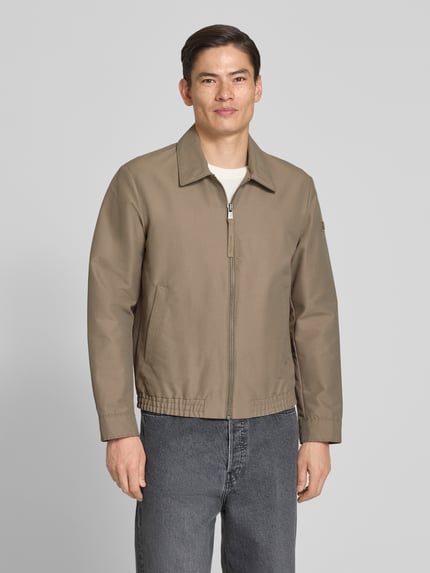 Männermodel trägt Regular Fit blouson met elastische rompzoom van Marc O'Polo in look: effen, met platte kraag, ritssluiting, labelpatch, lange mouw met drukknoop, zij-steekzakken en binnenzak, ganzkörperansicht von vorne.