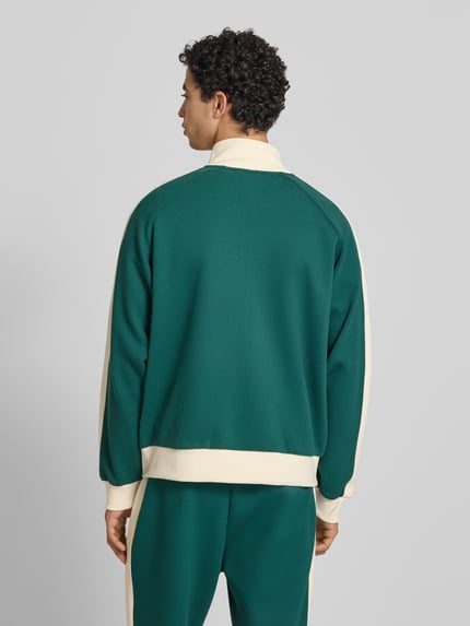 Männermodel trägt Regular Fit Sweatjacke mit Stehkragen von KARL KANI, grün mit cremefarbenen Details, Rückenansicht, Elastischer-Material-Mix, Reißverschluss, Logo-Stitching, Eingrifftaschen, elastische Abschlüsse, Herren, Rückenlänge 60 cm, Ärmellänge 48 cm. Ganzkörperansicht Rückansicht.