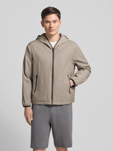 Männermodel trägt Jacke mit Zweiwege-Reißverschluss von Emporio Armani, Regular-Fit, Kapuze mit Tunnelzug, Reißverschlusstaschen, beige, Ganzkörperansicht von vorne. Rückenlänge 67 cm, Schulterbreite 54 cm, Brustweite 60 cm, Ärmellänge 63 cm, Größe 50.