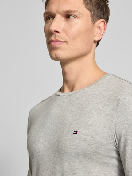 Männermodel trägt Slim Fit T-Shirt aus Baumwoll-Mix von Tommy Hilfiger, Optik: Unifarben, Label-Stitching-Applikation, Nahaufnahme Oberkörper