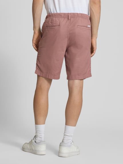Mannenmodel draagt Shorts met tunnelkoord model 'JAIDEN' van Jack & Jones in mix van katoen en linnen, regular fit, bandwijdte maat M 43 cm, binnenbeenlengte maat M 23 cm, roze tint, gladde textuur, volledig beeld van achteren.