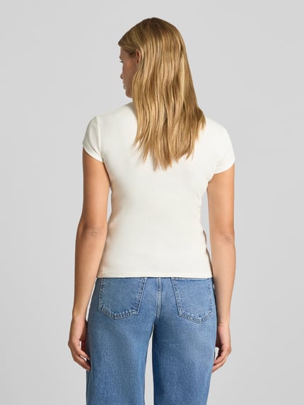 Frauenmodel trägt T-Shirt mit Rundhalsausschnitt Modell 'EVERYDAY' von Topshop in Creme, reine Baumwolle, gerader Schnitt, Ganzkörperansicht Rückansicht.