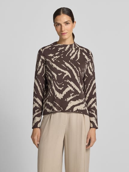 Kobiece modelka nosi sweter z dzianiny z mieszanki wiskozy w wzór na całej powierzchni, Stójka, krój regular fit, dł. tyłu 53 cm, dł. rękawów 58 cm, Strickpullover aus Viskose-Mix im Allover-Look von COMMA, kolor brązowy i beżowy, faktura miękka, widok całej sylwetki z przodu.