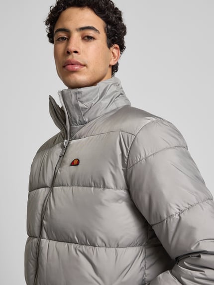 Mannenmodel draagt Regular Fit Steppjacke met Logo-Stitching model 'Paddero' van Ellesse in lichtgrijs, gewatteerde look, Nahaufnahme bovenlichaam.