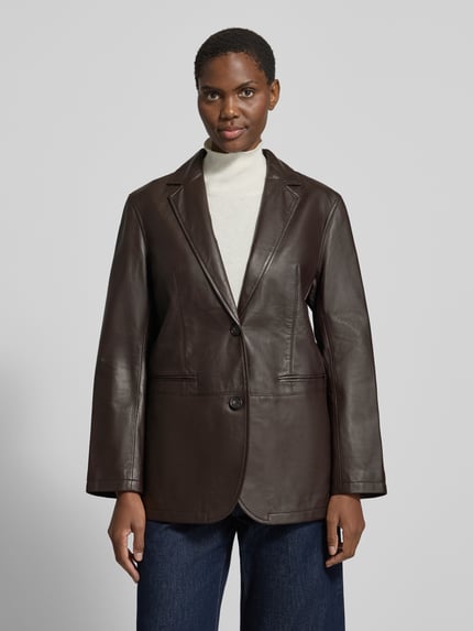 Frauenmodel trägt Regular Fit Longline Lederjacke aus Lammnappa von Marc O'Polo in einfarbiger Lederoptik mit Struktur, Paspeltaschen, Knöpfen und Teilungsnähten, Ganzkörperansicht von vorne.