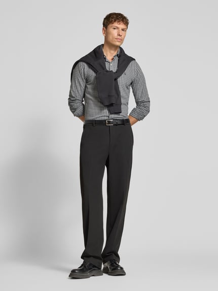 Männermodel trägt Regular Fit Freizeithemd aus reiner Baumwolle von Polo Ralph Lauren in Grau mit feinem Karomuster, schwarze Stoffhose, Ganzkörperansicht von vorne. Herren Freizeithemd von Polo Ralph Lauren.