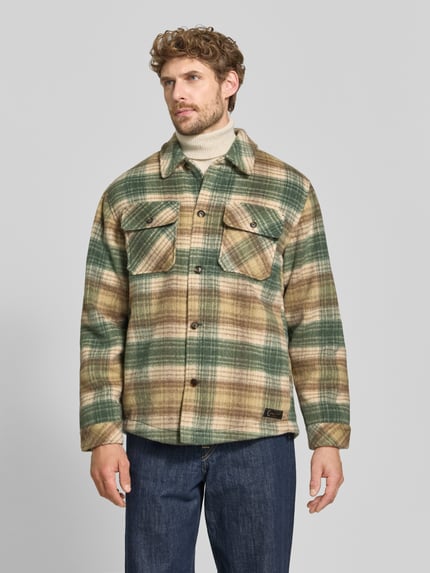 Männermodel trägt Regular Fit Hemdjacke mit Brusttaschen von Scotch & Soda, grünes und beigefarbenes Karo, Kentkragen, Knopfleiste, Ganzkörperansicht von vorne. Mix mit Woll-Anteil, Allover-Look, Rückenlänge bei Größe M: 72 cm.