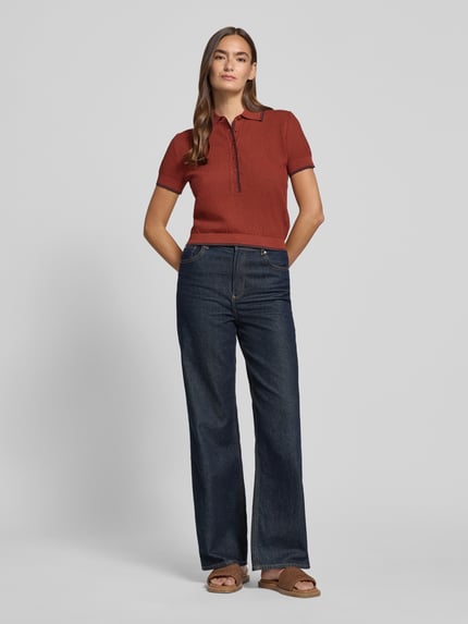 Kobiece model nosi Strickshirt mit Polokragen und Knopfleiste Modell 'MEROPE' von DRYKORN z bawełny, krój regular fit, długość tyłu 50 cm, długość rękawów 20 cm, widok całej sylwetki z przodu.