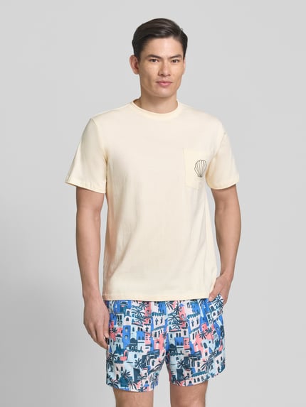 Männermodel trägt T-Shirt mit Brusttasche und Stitching Modell 'Ilfracombe' von BOARDIES, Reine Baumwolle, Regular-Fit, Rundhalsausschnitt, Creme, Brusttasche mit Stickerei, Rückenlänge bei Größe M 71 cm, Ganzkörperansicht von vorne.