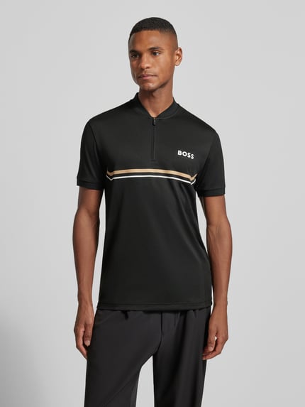 Männermodel trägt Slim Fit Poloshirt mit Logo-Print Modell 'TOC SPIN BODYMAPP 1027' von BOSS Green in Schwarz mit Serafino-Kragen, Ganzkörperansicht von vorne.