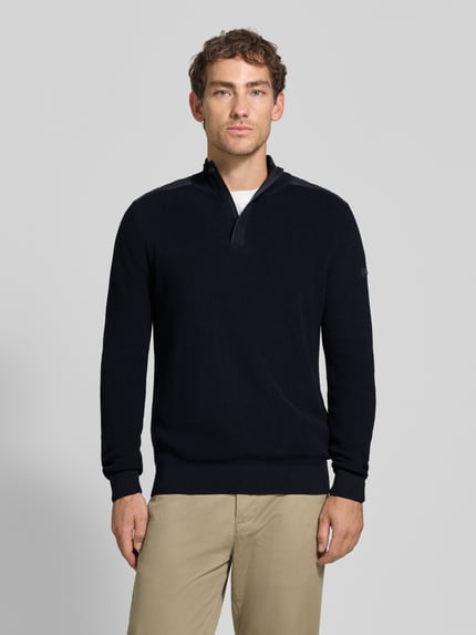 Männermodel trägt gebreide pullover met schoudervullingen van bugatti in donkerblauw, puur katoen, recht model, schipperskraag, ribboorden, ruglengte bij maat M 68 cm, mouwlengte bij maat M 70 cm, ganzkörperansicht van voren.