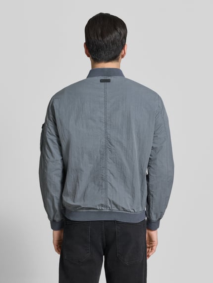 Mannenmodel draagt Blouson met Label-Patches Model 'IBE' van khujo in grijs met rechte fit, korte opstaande kraag, rugaanzicht volledige lichaamsopname.