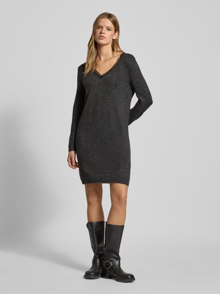 Frauenmodel trägt tailliertes, knielanges Strickkleid mit V-Ausschnitt Modell 'TAMMY' von Only in Melange-Optik, Ganzkörperansicht von vorne.