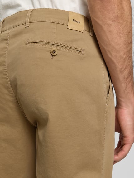 Männermodel trägt Gerade Hose aus Viskose-Mix Modell 'Everest' von Brax in Beige, glatte Textur, Nahaufnahme Rückansicht, Herrenmode.