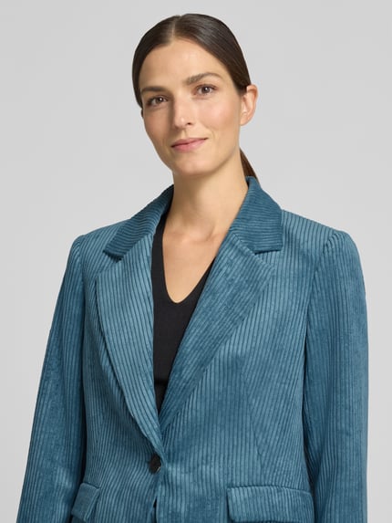 Frauenmodel trägt Slim Fit Blazer aus Cord mit Pattentaschen von COMMA in Blau, strukturierte Oberfläche, Nahaufnahme Oberkörper.