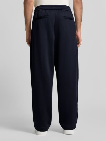 Männermodel trägt Wide Fit Sweathose mit elastischem Bund von Armani Exchange, dunkelblau, Baumwoll-Mix, Gesäßtaschen, Ganzkörperansicht Rückansicht.