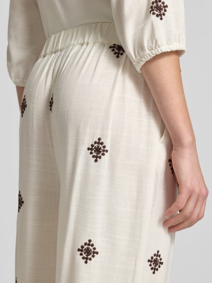 Frauenmodel trägt Hose aus Viskose-Leinen-Mix mit Stitchings von Christian Berg Woman Selection, cremefarben mit braunem Muster, Nahaufnahme Rückansicht. Regular Fit, elastischer Bund, leichte und strukturierte Textur.