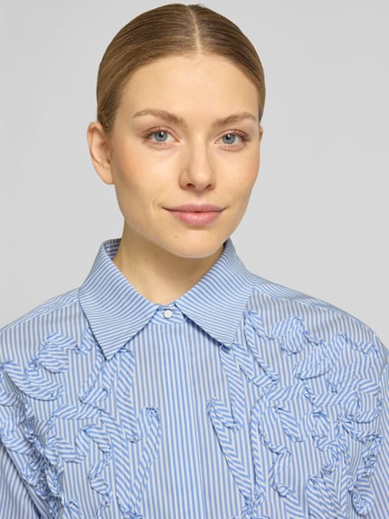Frauenmodel trägt Regular Fit Bluse mit Stitchings von Marc Cain, blau-weiß gestreift, Baumwoll-Mix mit Stretch, Nahaufnahme Oberkörper.