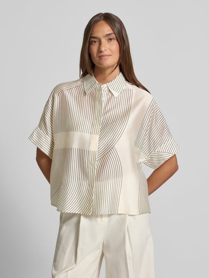 Frauenmodel trägt Boxy Fit Bluse aus Lyocell-Mix Modell 'Zulin' von Someday, cremefarben mit schwarzen Linien, Hemdblusenkragen, verdeckte Knopfleiste, Damen Bluse, Rückenlänge bei Größe 36: 60 cm, Ärmellänge bei Größe 36: 20 cm, Ganzkörperansicht von vorne.