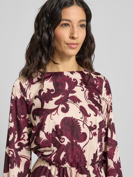 Frauenmodel trägt Cocktailkleid mit Rundhalsausschnitt von Rinascimento aus Material-Mix mit Stretch-Anteil, Plisseefalten, körpernahe Passform, Nahaufnahme Oberkörper.