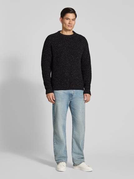 Männermodel trägt Pullover mit Raglanärmeln Modell 'KIAANO' von ARMEDANGELS, schwarze Melange-Strickoptik, Rundhals, Ganzkörperansicht von vorne.