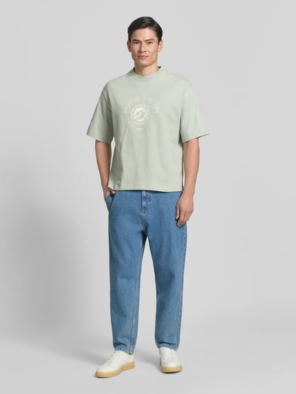Männermodel trägt Relaxed Fit T-Shirt aus reiner Baumwolle Modell 'BOXYNORMAN GRAPHIC' von SELECTED HOMME in Mintgrün, kurze Ärmel, Motiv-Print auf Jersey, Ganzkörperansicht von vorne