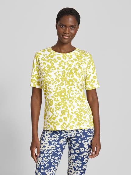 Frauenmodel trägt T-Shirt im Allover-Look mit Rundhalsausschnitt von Marc Cain in Gelb-Weiß, Baumwoll-Elasthan-Mix, Regular Fit, Ganzkörperansicht von vorne.