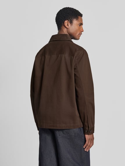 Männermodel trägt Regular Fit Freizeithemd aus reiner Baumwolle von GANT in Dunkelbraun, glatte Textur, Ganzkörperansicht Rückansicht.