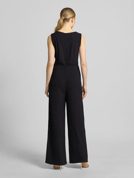 Frauenmodel trägt schwarzen Jumpsuit mit Bindegürtel Modell 'Jessica' von GUIDO MARIA KRETSCHMER WOMAN, Taillierter Schnitt, Rückenreißverschluss, Ganzkörperansicht Rückansicht.