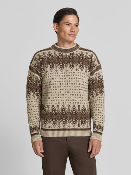 Männermodel trägt Regular Fit Pullover aus reiner Wolle Modell 'Albertville' von Dale of Norway in Beige-Braun mit Strick-Optik, Ganzkörperansicht von vorne, Rückenlänge 66 cm, Ärmellänge 59 cm.