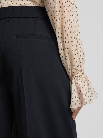 Frauenmodel trägt Barrel Fit Hose Modell 'Moira Bloom' von OPUS PANTS, dunkelblauer Baumwoll-Mix mit Bügelfalten, Detailaufnahme Rückansicht.