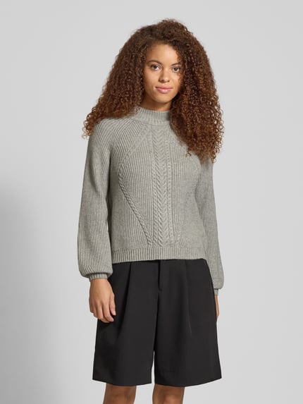 Frauenmodel trägt Regular Fit Strickpullover aus Viskose-Mix Modell 'KATIA' von Only in Melange-Optik mit Zopfmuster und Mock Neck, Nahaufnahme Oberkörper.