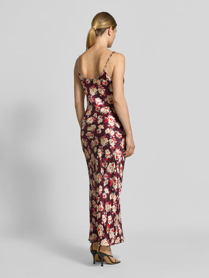 Frauenmodel trägt Maxikleid aus reiner Seide von Rabanne in Dunkelrot mit floralen Mustern, figurbetont, Spaghettiträger aus Gliederketten, Maxilänge, ärmellos, glatte Textur, Ganzkörperansicht Rückansicht.