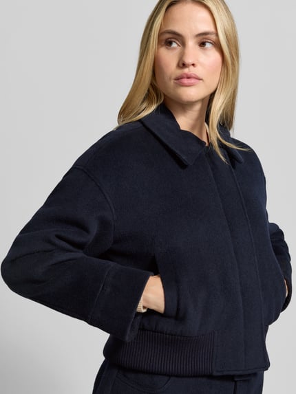 Frauenmodel trägt Wolljacke aus Woll-Viskose-Mix von Self-Portrait in Dunkelblau, Kunstfellbesatz, Regular Fit, Nahaufnahme Oberkörper.