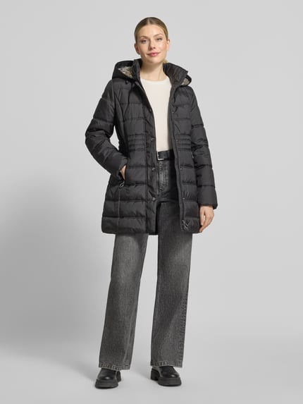 Frauenmodel trägt Steppmantel mit Kapuze Modell 'LT SEPTEMBER' von BETTY BARCLAY in Schwarz, Longline, strukturierte Webware, Zierknöpfe, Reißverschlusstaschen, Ganzkörperansicht von vorne.