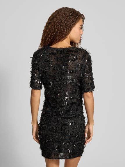 Frauenmodel trägt Cropped Blusentop mit Paillettenfransen von PIECES, schwarze Struktur, Webware, Fransenoptik, Rückansicht, Ganzkörperansicht.