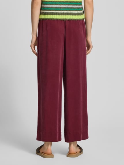 Vrouwenmodel draagt Weite Hose aus Lyocell van Marc O'Polo Denim in effen kleuren, regular fit, wide leg, mid waist, labelpatch, elastische boord, zij-steekzakken, materiaal: lyocell. Volledige lichaamsaanzicht achterkant.