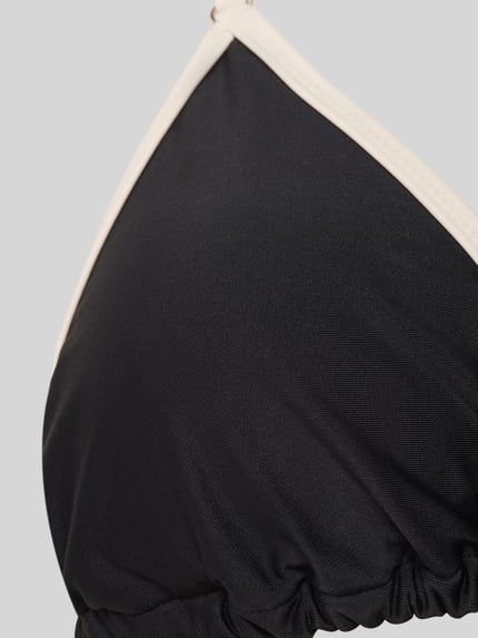 Frauenmodel trägt Slim Fit Bikini Set in Triangel-Optik von Shiwi aus Elastischer-Material-Mix, schwarze glatte Oberfläche, Detailaufnahme.