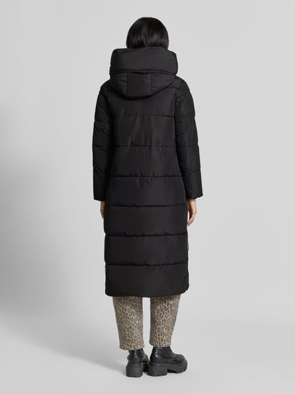 Frauenmodel trägt Regular Fit Mantel in Stepp-Optik Modell 'SOULANI' von khujo in Schwarz mit Kapuze, Ganzkörperansicht Rückansicht. Damen Mantel, Eingrifftaschen, Stehkragen, Rückenlänge 117 cm, Schulterbreite 43 cm, Brustweite 50 cm, Ärmellänge 62 cm.